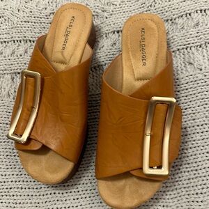 Camel color sandals with gold buckles and wood platform style bottoms.